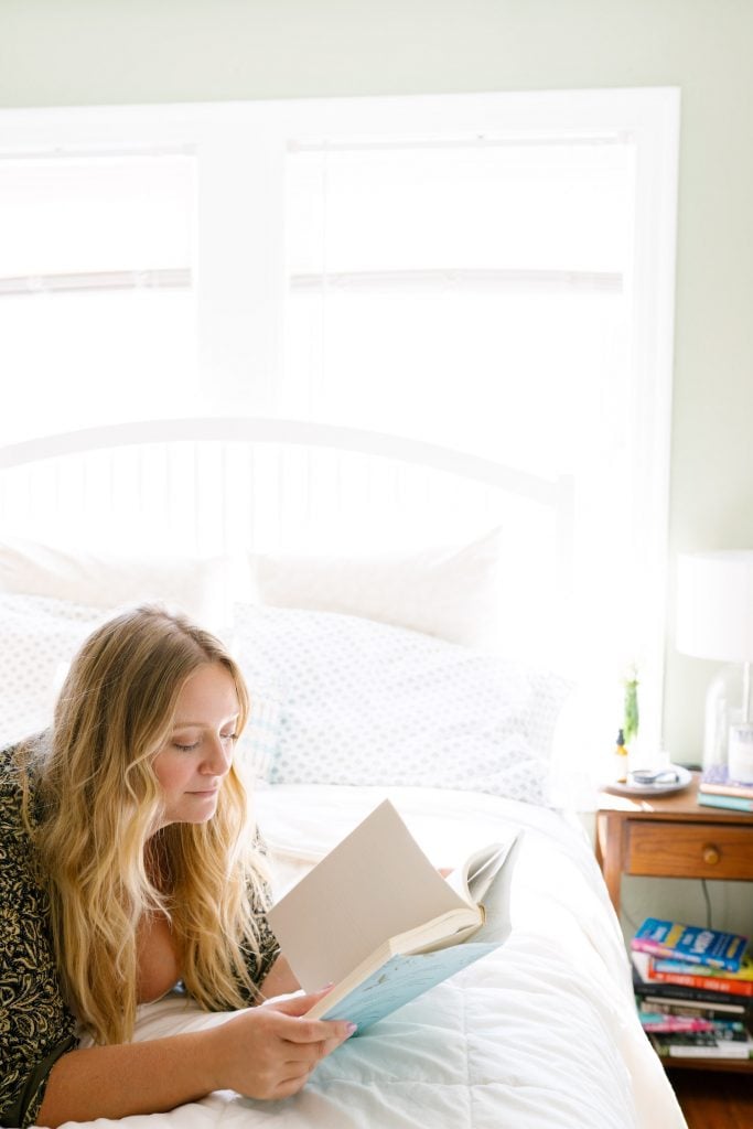 Blonde woman reading on bed.