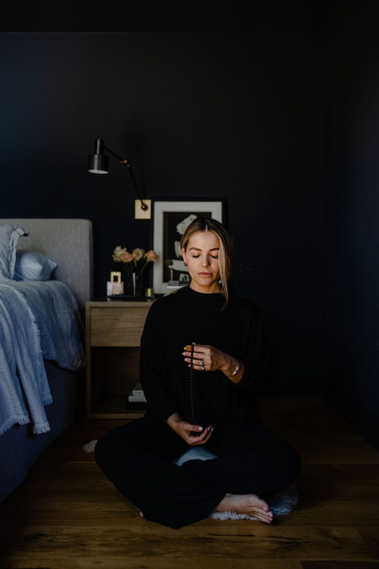 Woman meditating in bedroom.