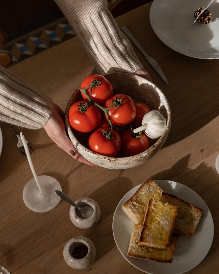 Bowl of tomatoes and bread on table.