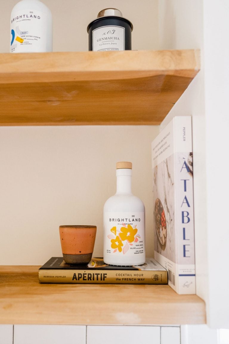 Olive oil and cookbooks on kitchen shelves.