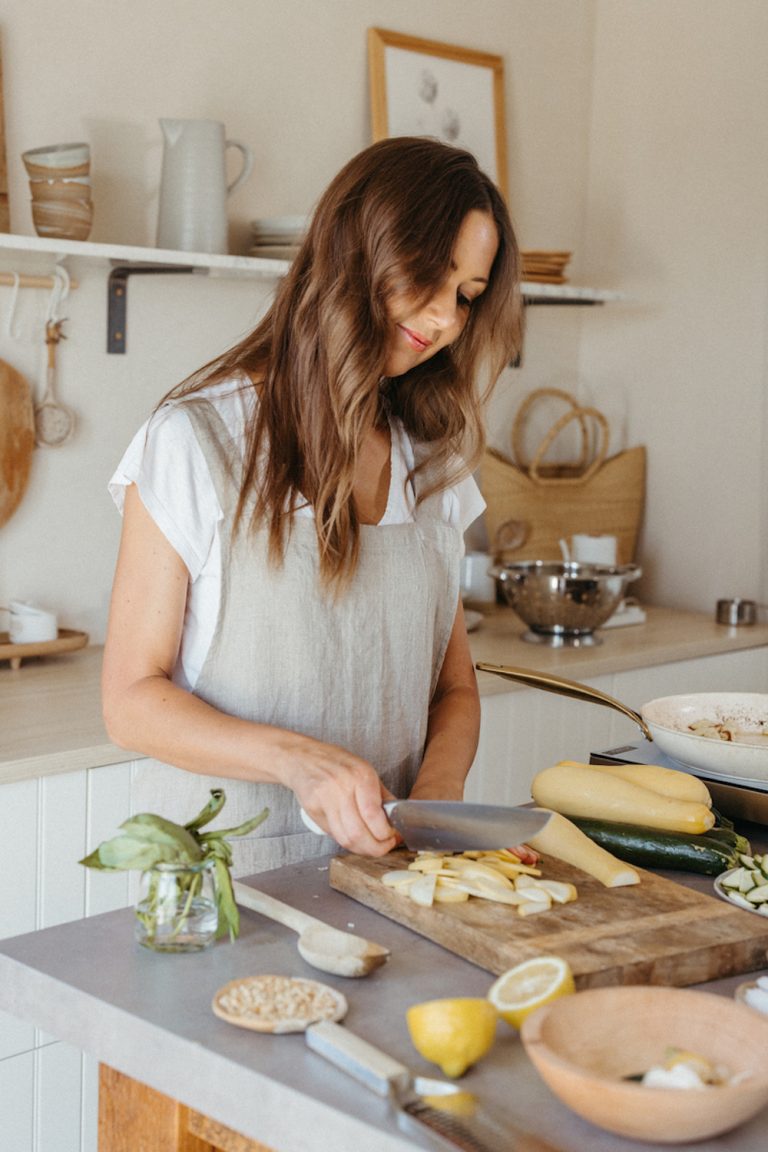 Woman chopping up vegetables in kitchen.