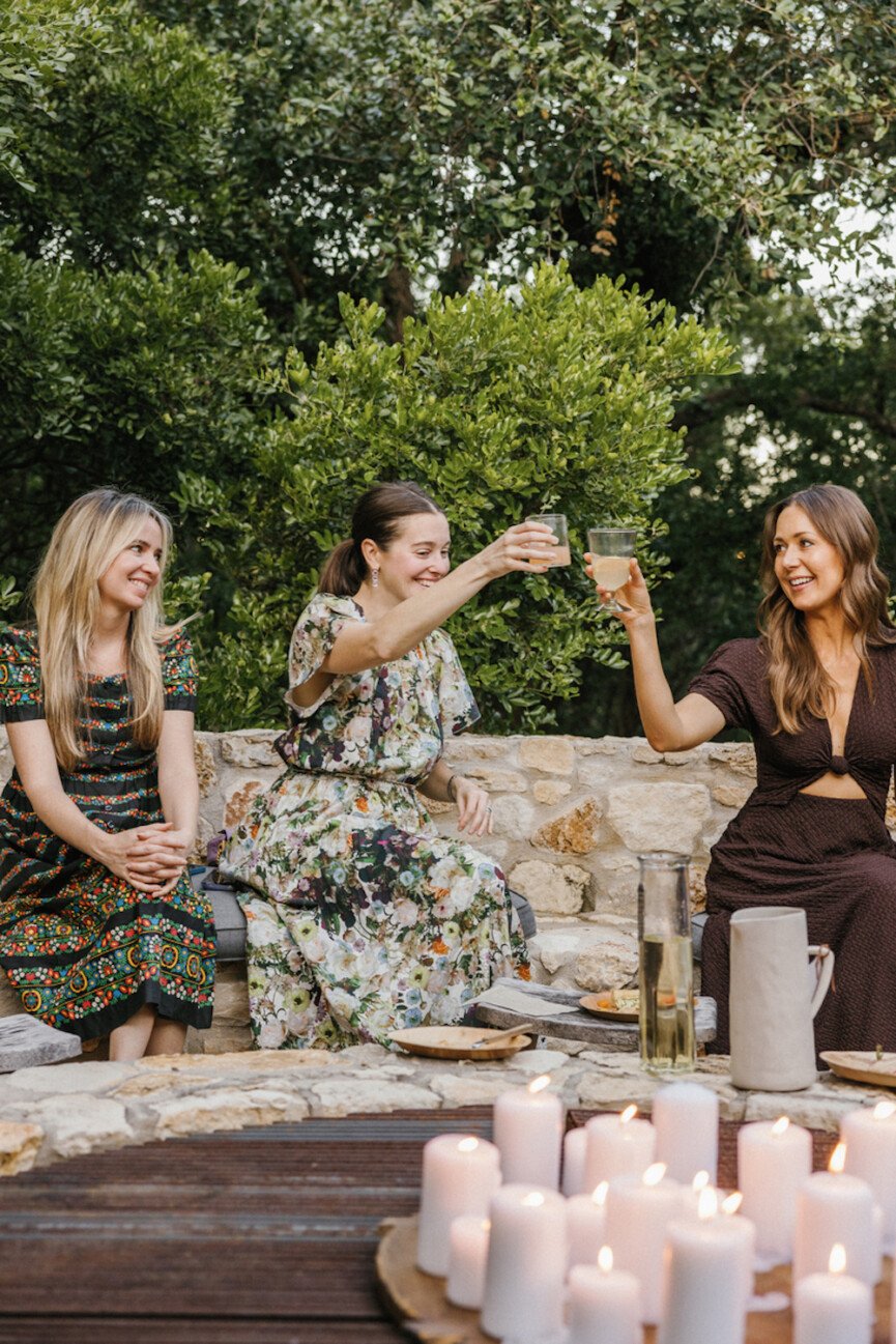 Mulheres brindando com copos do lado de fora.