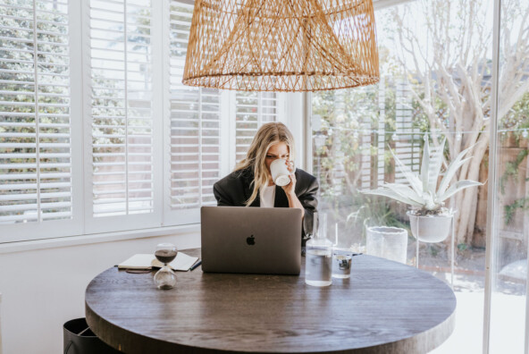 Woman drinking coffee at desk.