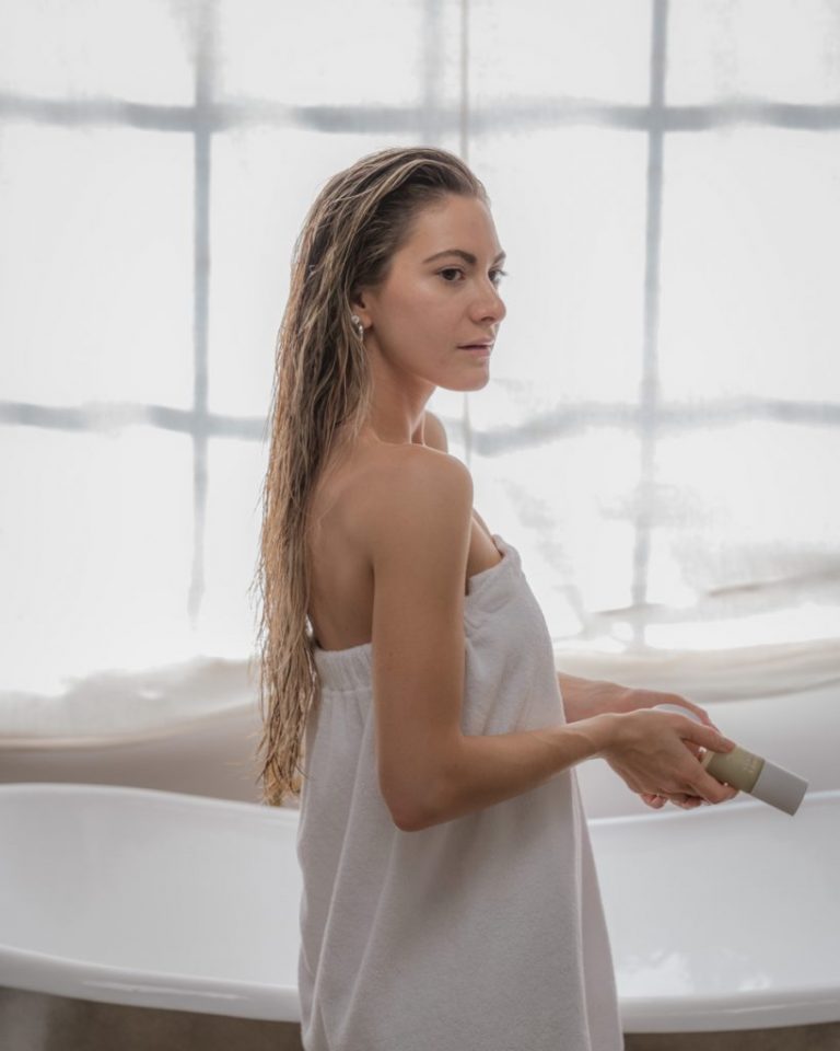 Woman wearing white towel in bathroom.