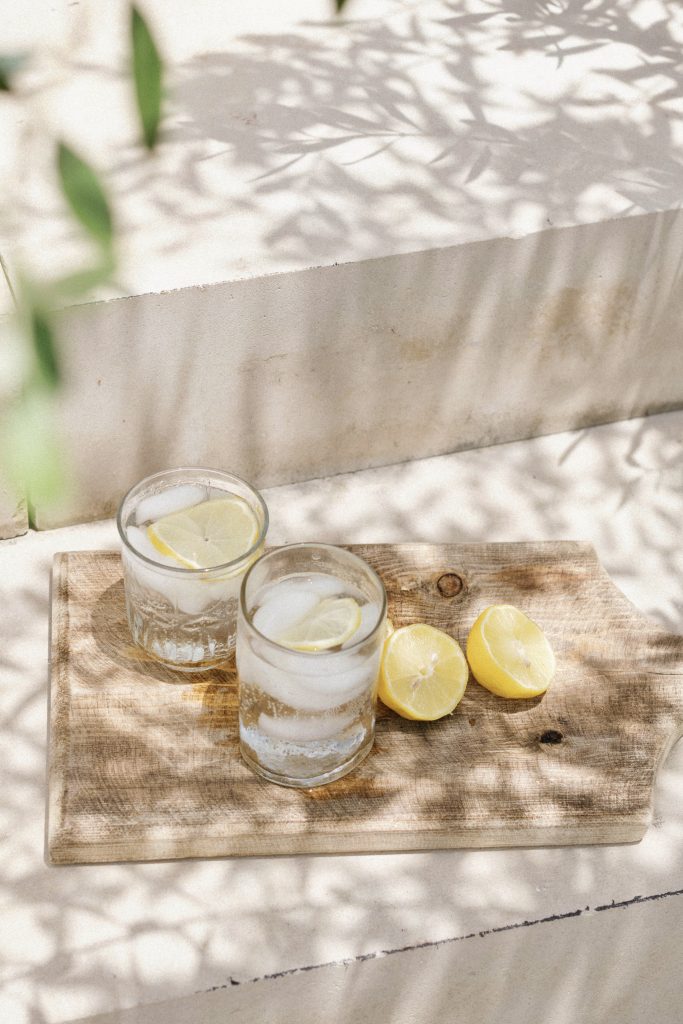 Glasses of lemon water on wooden cutting board.