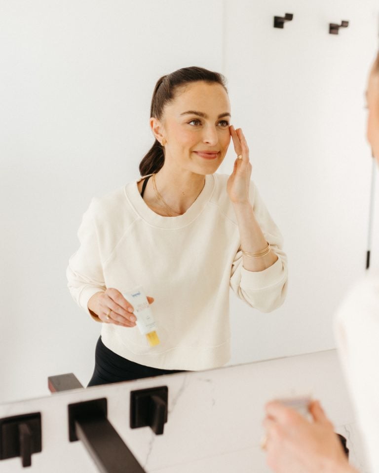 Megan Roup applying skincare in mirror.