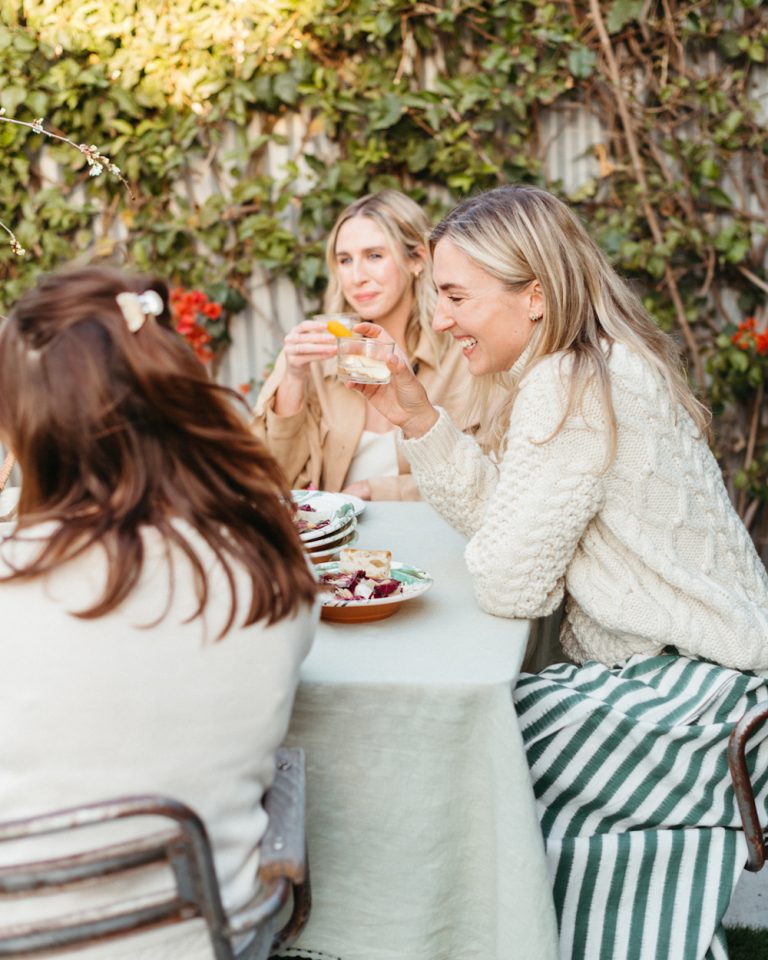 Women laughing at outdoor dining table.