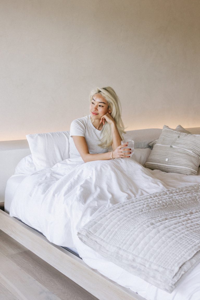 Woman sitting in bed drinking water.