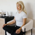 Woman doing somatic breathwork in chair.