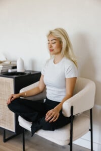 Woman doing somatic breathwork in chair.