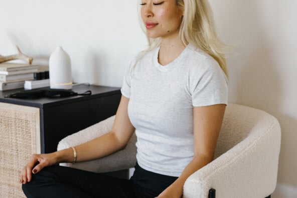 Woman doing somatic breathwork in chair.