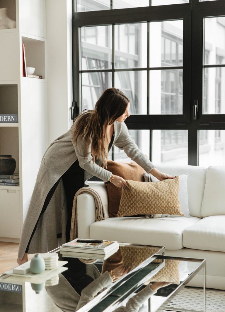 Woman arranging cushions on couch.