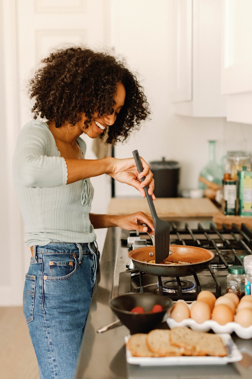 Woman cooking eggs in kitchen.