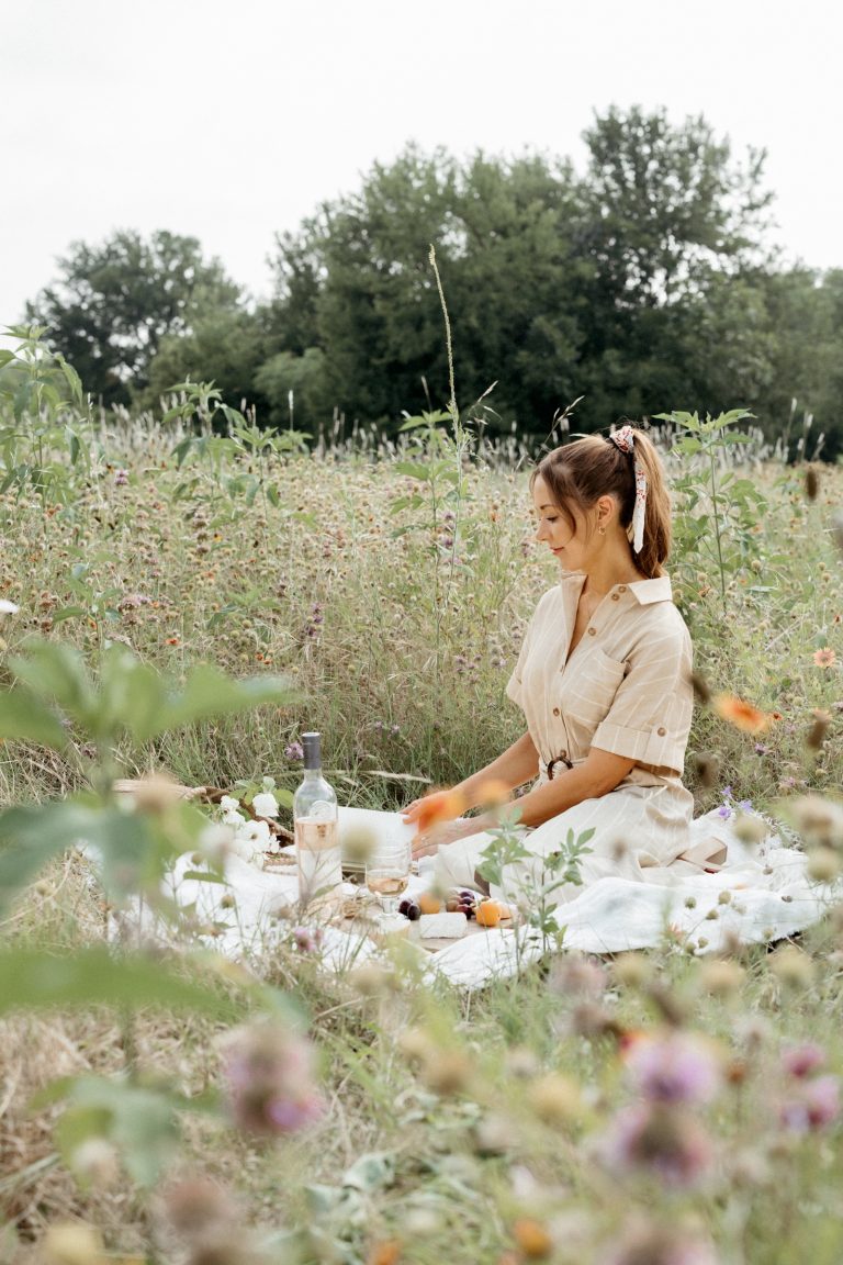 camille styles sitting in a field of flowers with picnic 