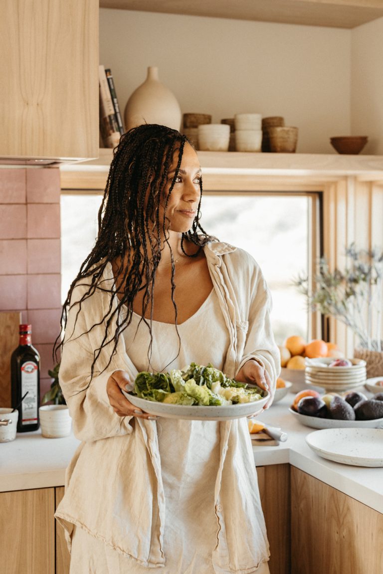 Woman in kitchen holding salad bowl.