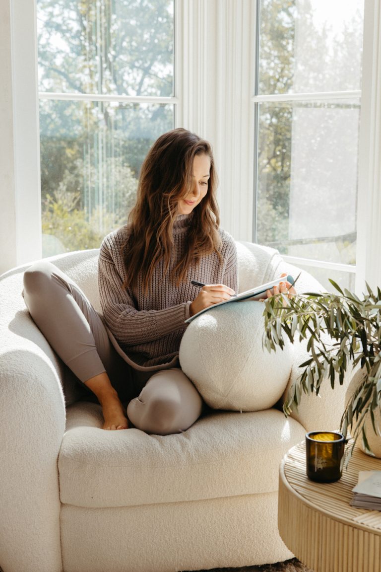 Camille Styles journaling in cozy armchair.