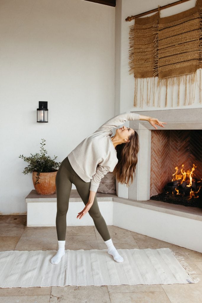 Camille Styles stretching in front of fireplace.