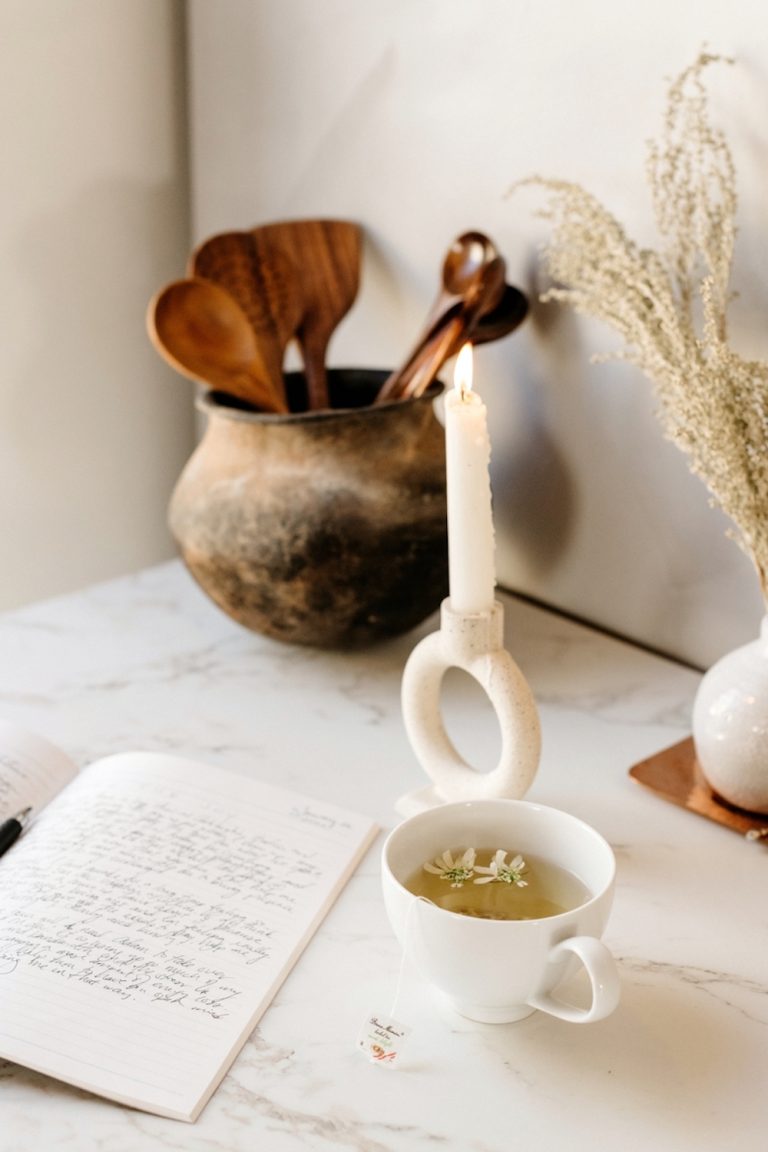 Cup of herbal tea, journal, and candle.