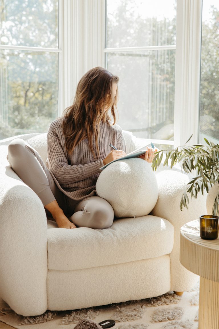 Woman journaling in armchair.