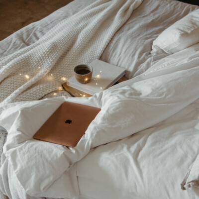 laptop on cozy bed with twinkle lights for a fall movie night