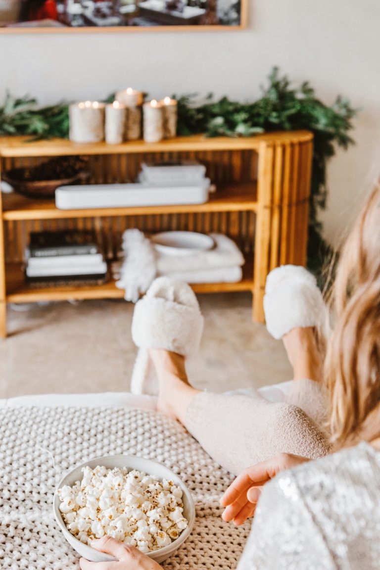 Woman watching television eating popcorn.