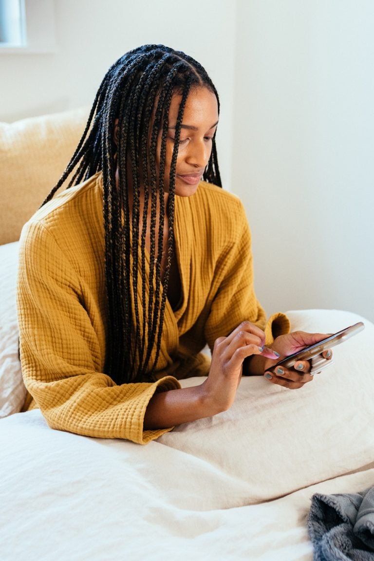 Woman using phone in bed.