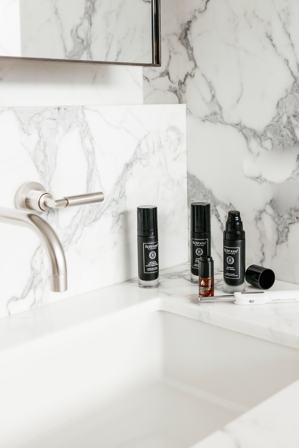 Beauty products on marble bathroom counter.
