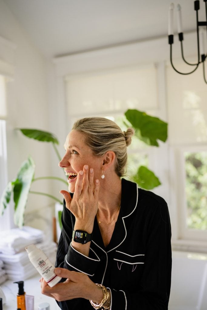 Woman applying facial moisturizer.