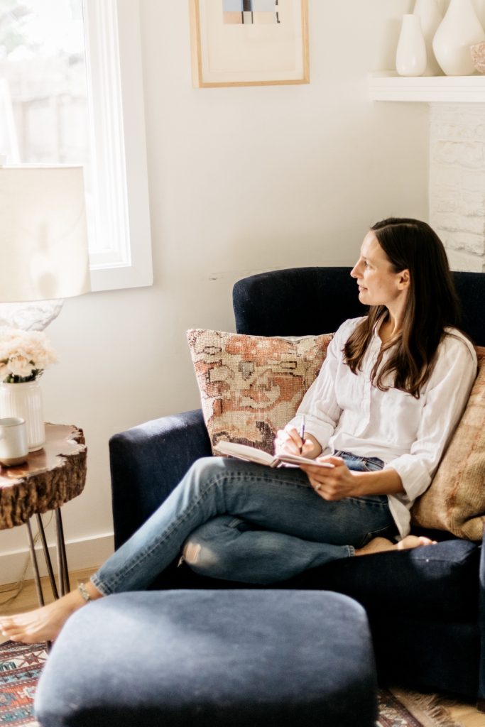 Woman journaling in armchair.