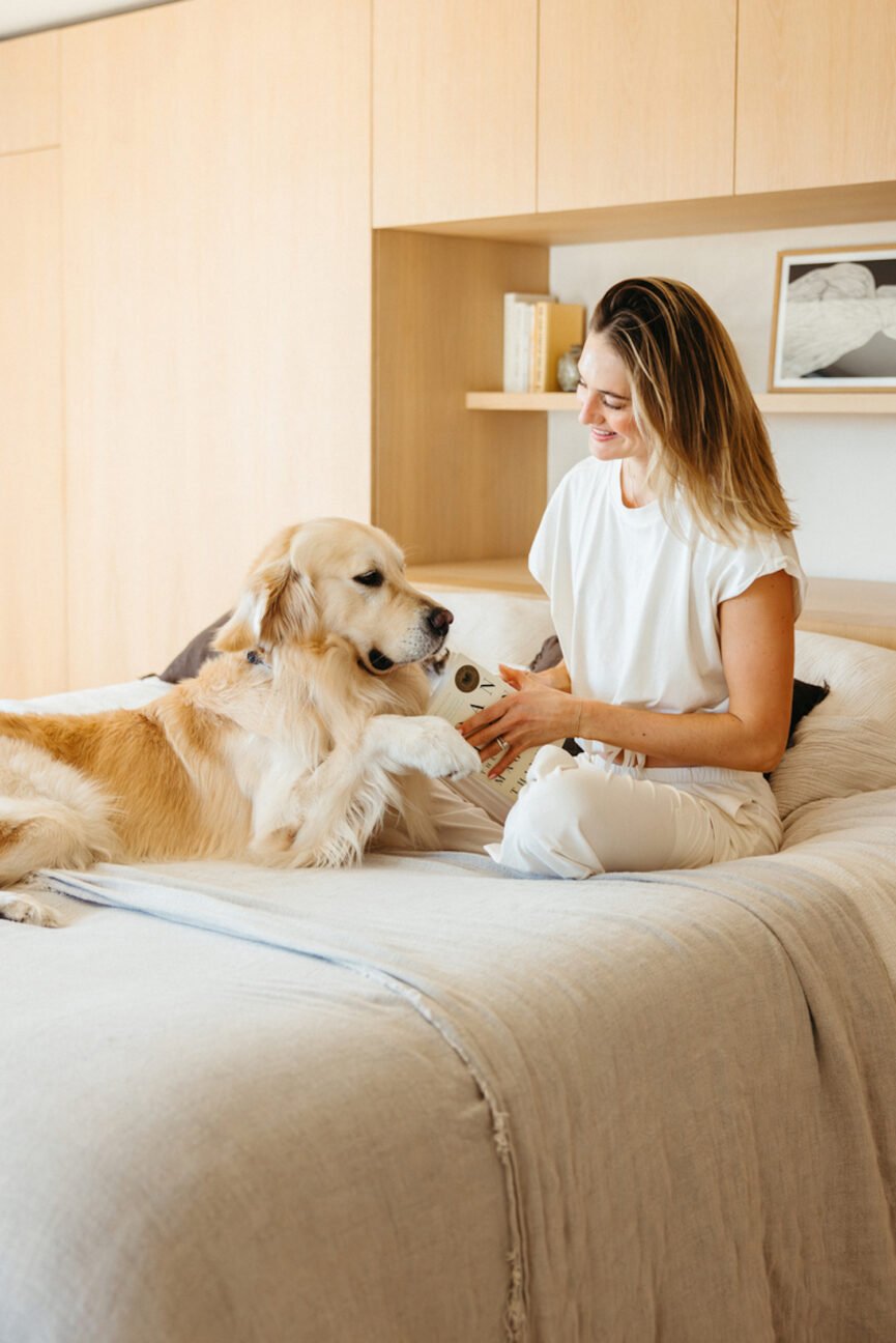 Woman reading the best self-help books in bed while petting dog.