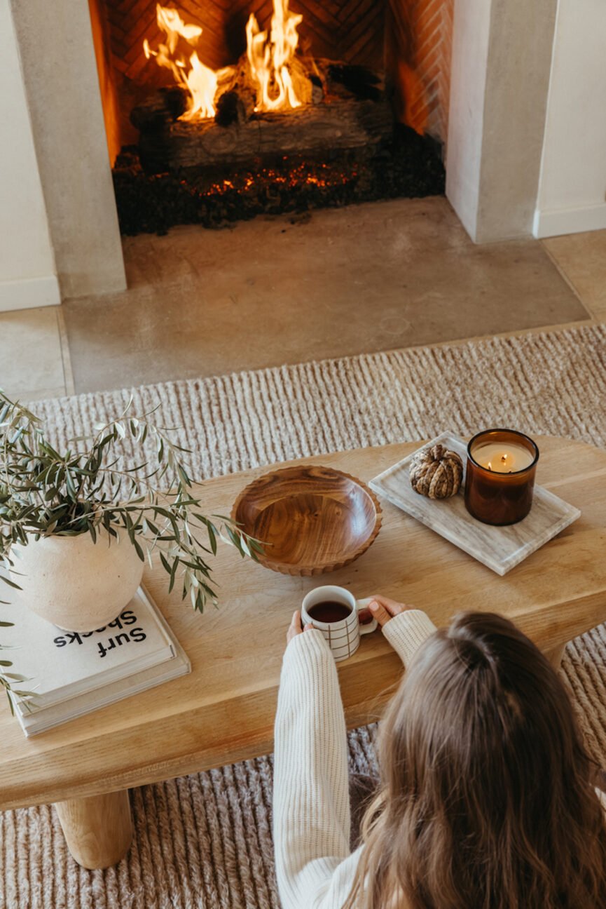 Camille Styles sitting in front of the fireplace.