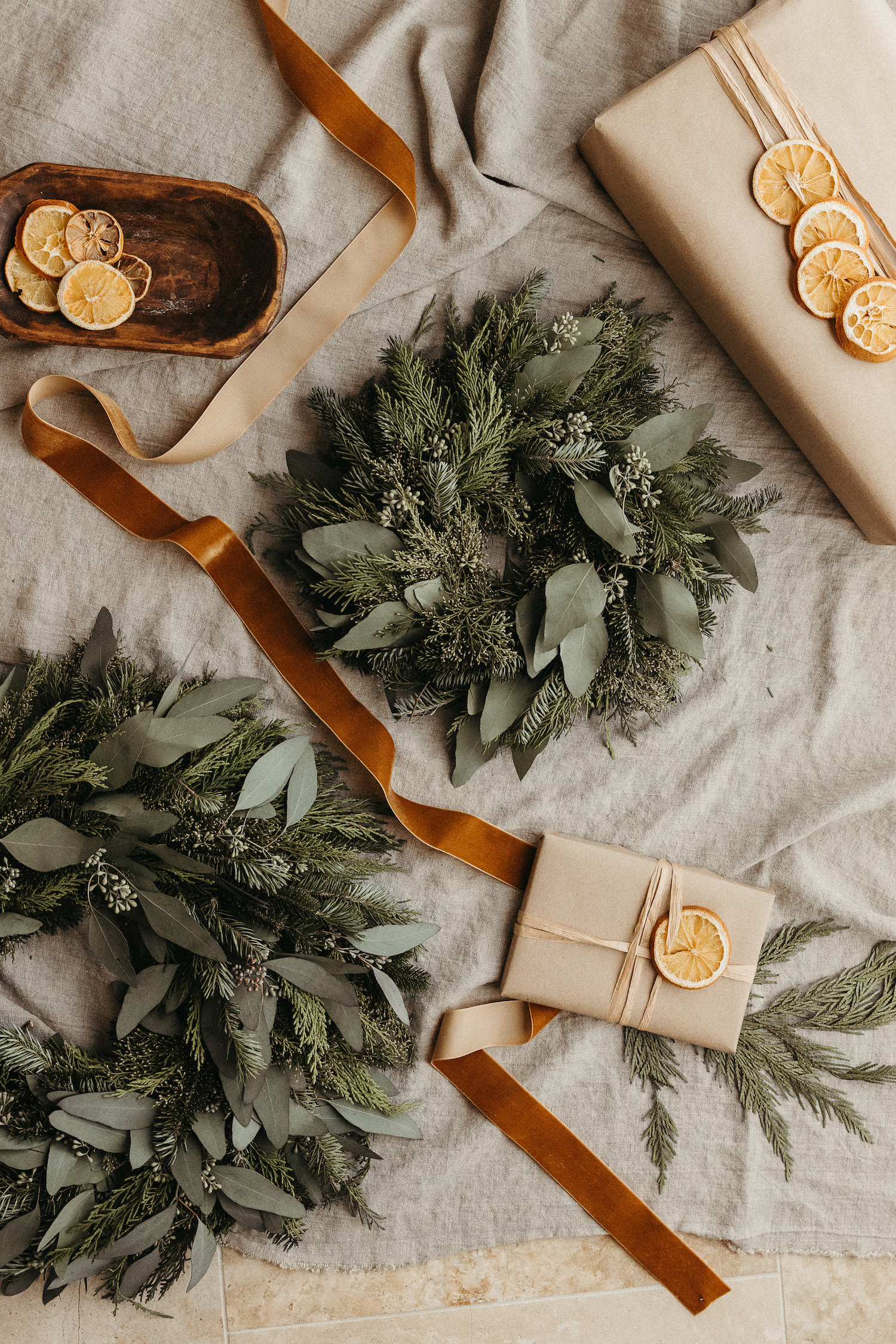 Camille Styles Holiday Decor 2023-Christmas tree with kraft paper presents and dried citrus-rustic gift wrapping and evergreen casa zuma holiday wreath