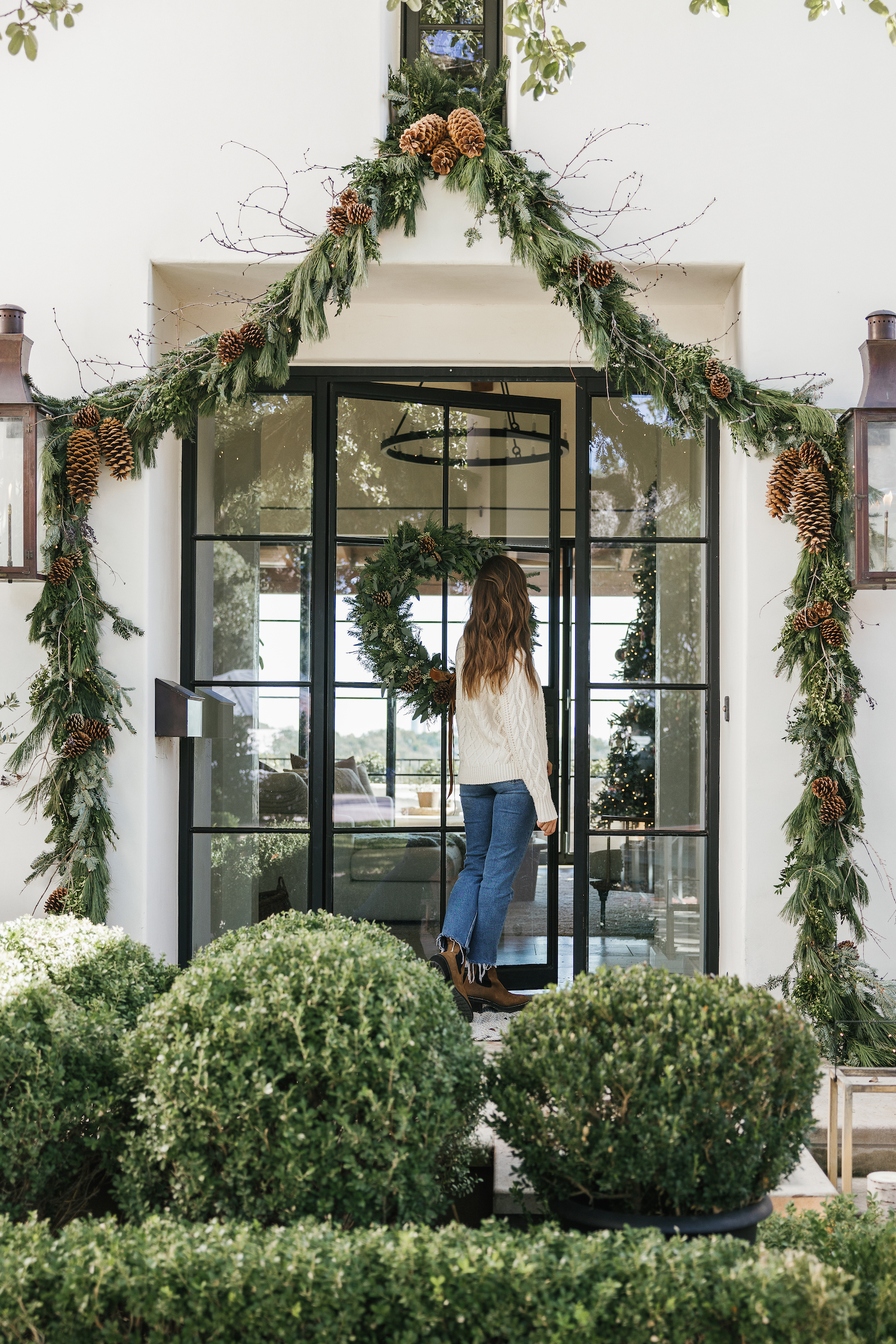 Camille Styles Holiday Decor 2023-Christmas front porch decor with evergreen garland and casa zuma holiday wreath and candles