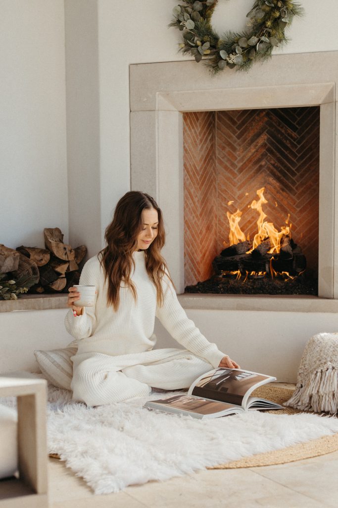 Woman reading by fireplace.