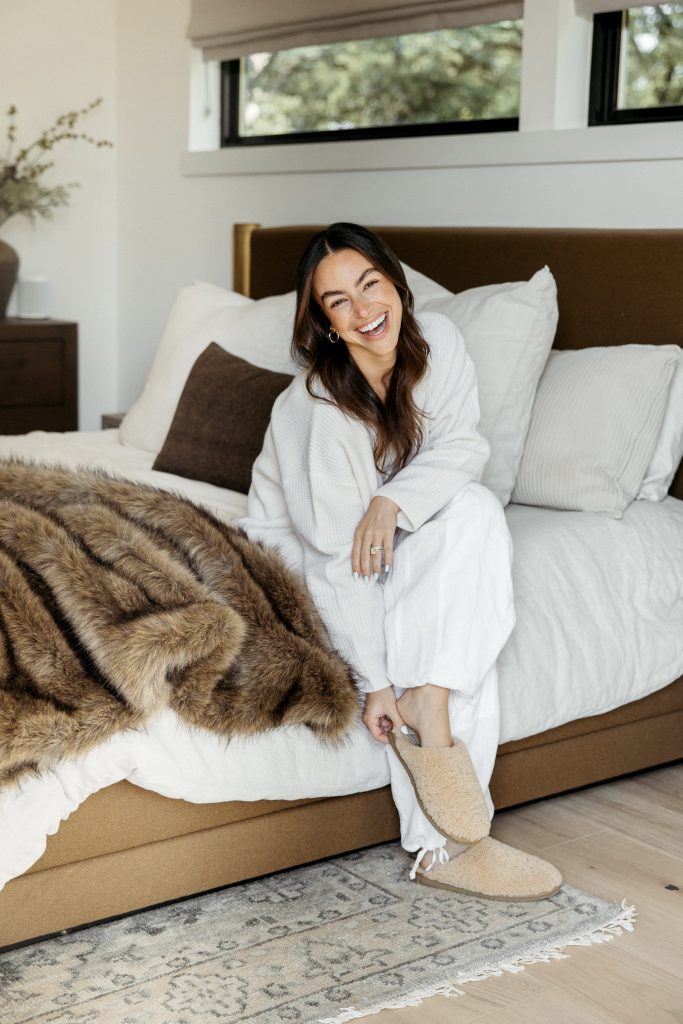 Woman sitting on bed wearing loungewear.