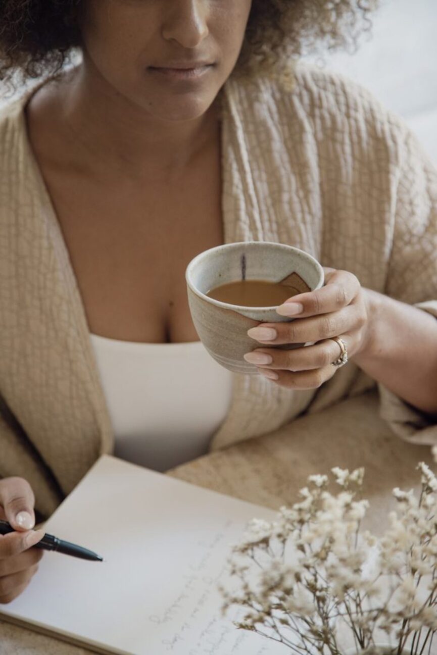 Woman journaling and drinking coffee.