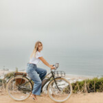 Woman biking by ocean.