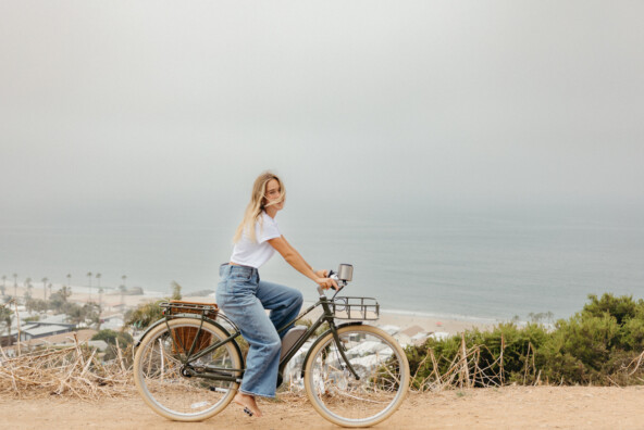 Woman biking by ocean.
