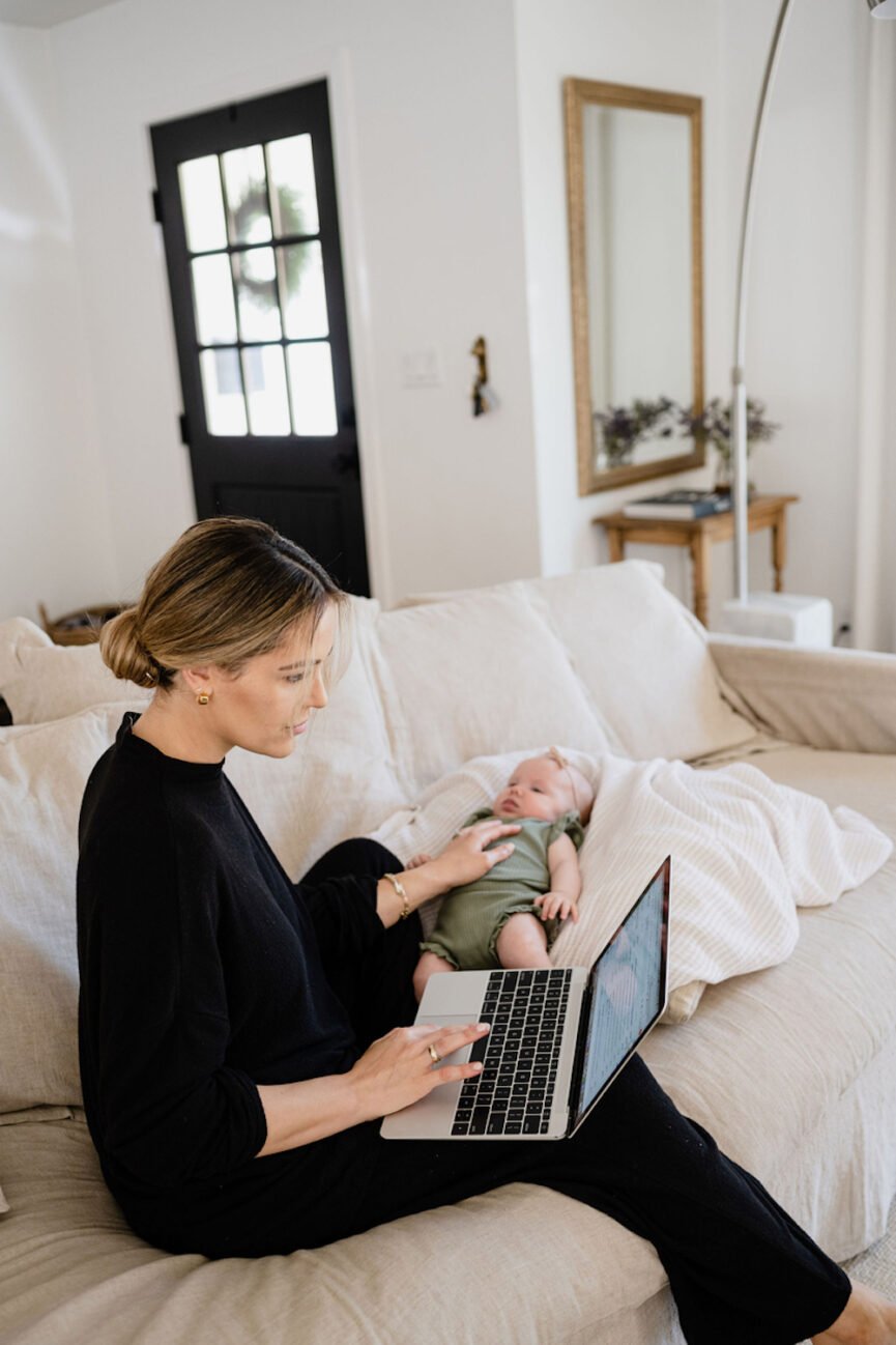 Woman working on laptop with baby.