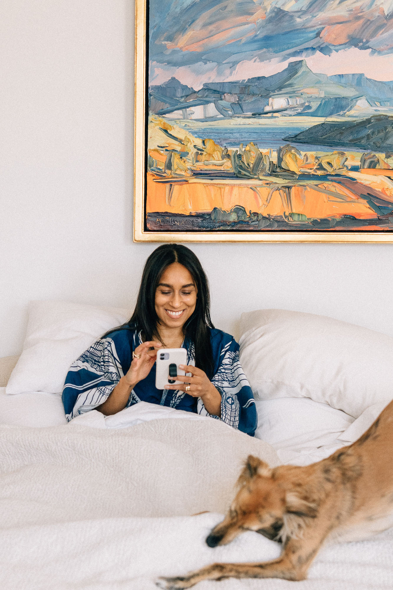 woman smiling in bed organizing photos on phone