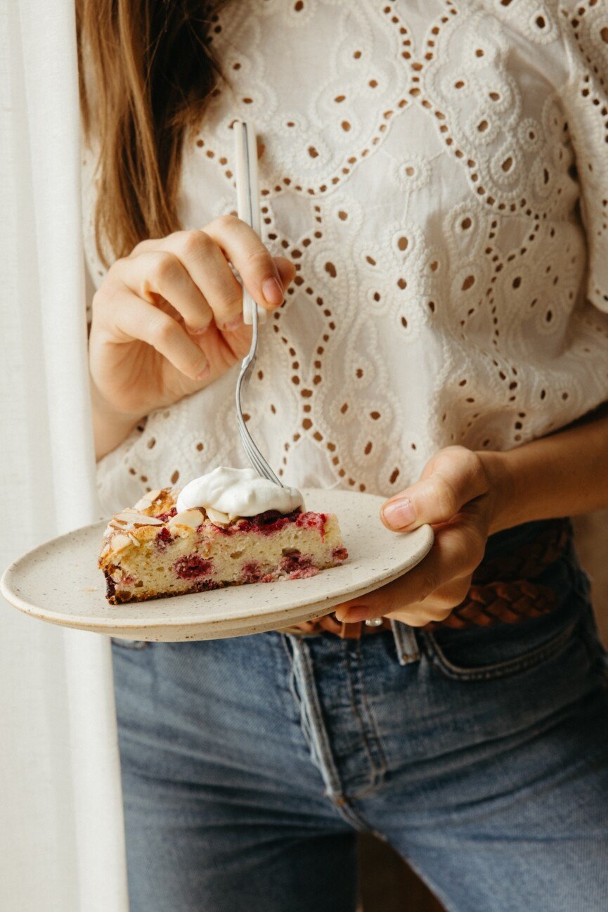 slice of raspberry cake with whipped cream on top and fork going in