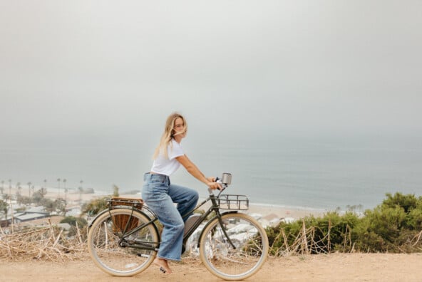 Blonde woman biking by ocean.