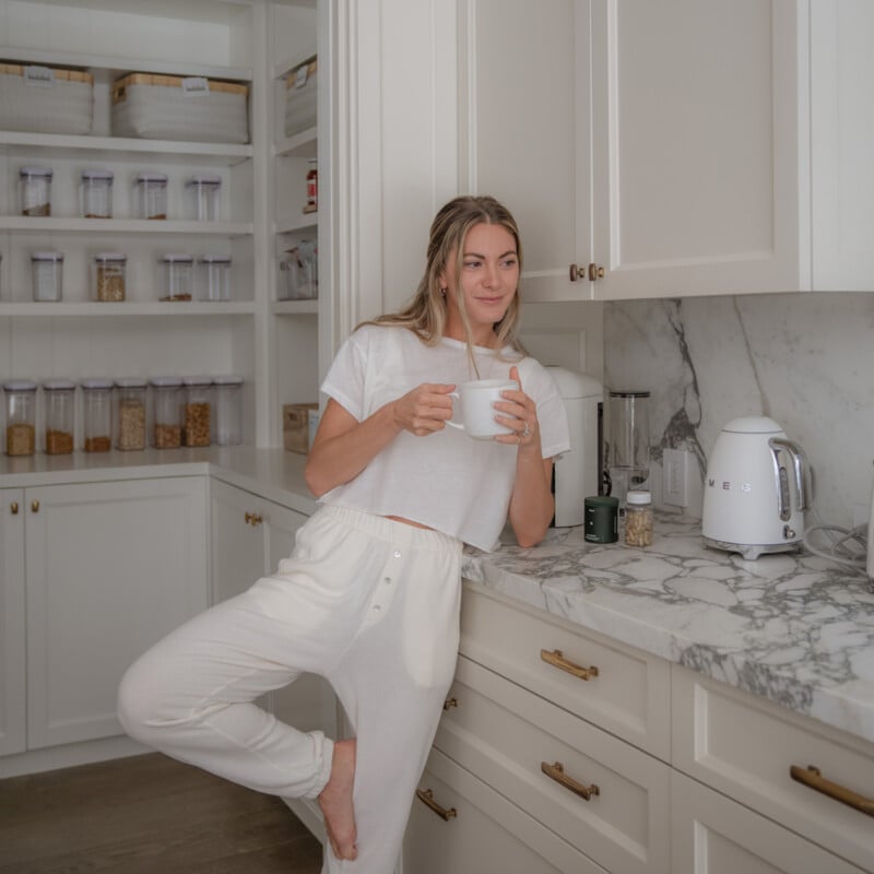 Woman drinking coffee in kitchen.