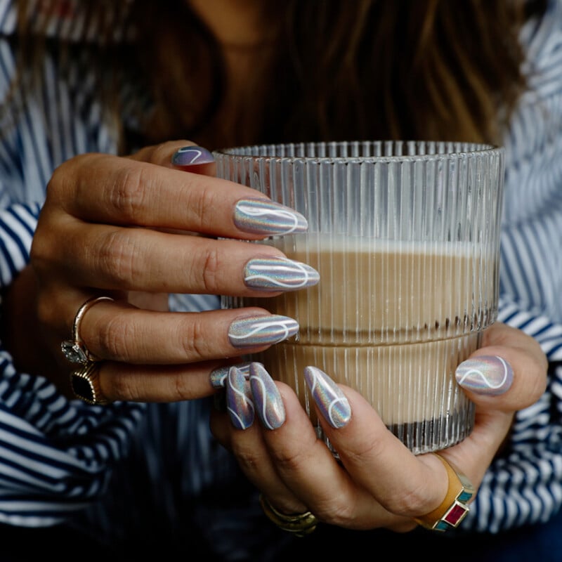 Woman holding latte with bold nails.