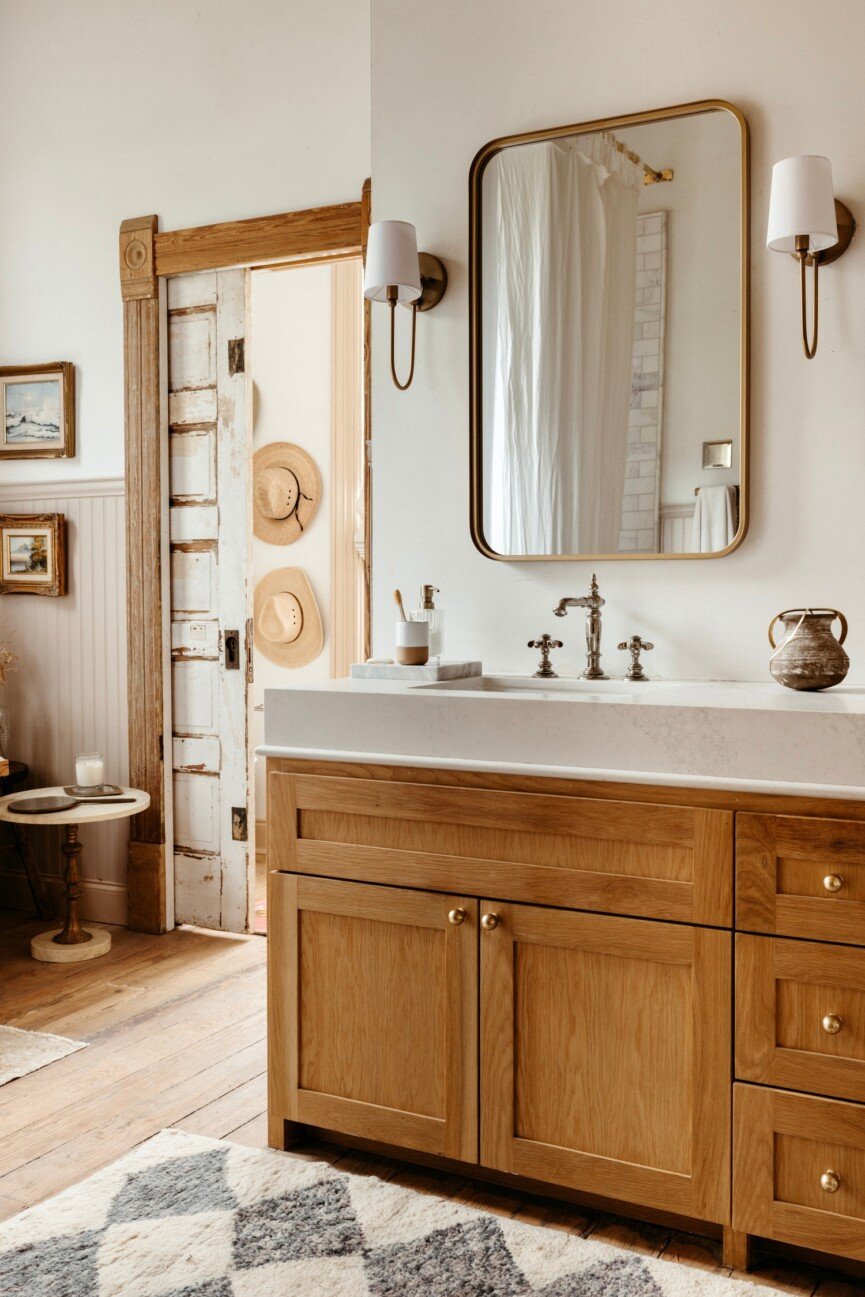 A bathroom with warm wood and wall sconces