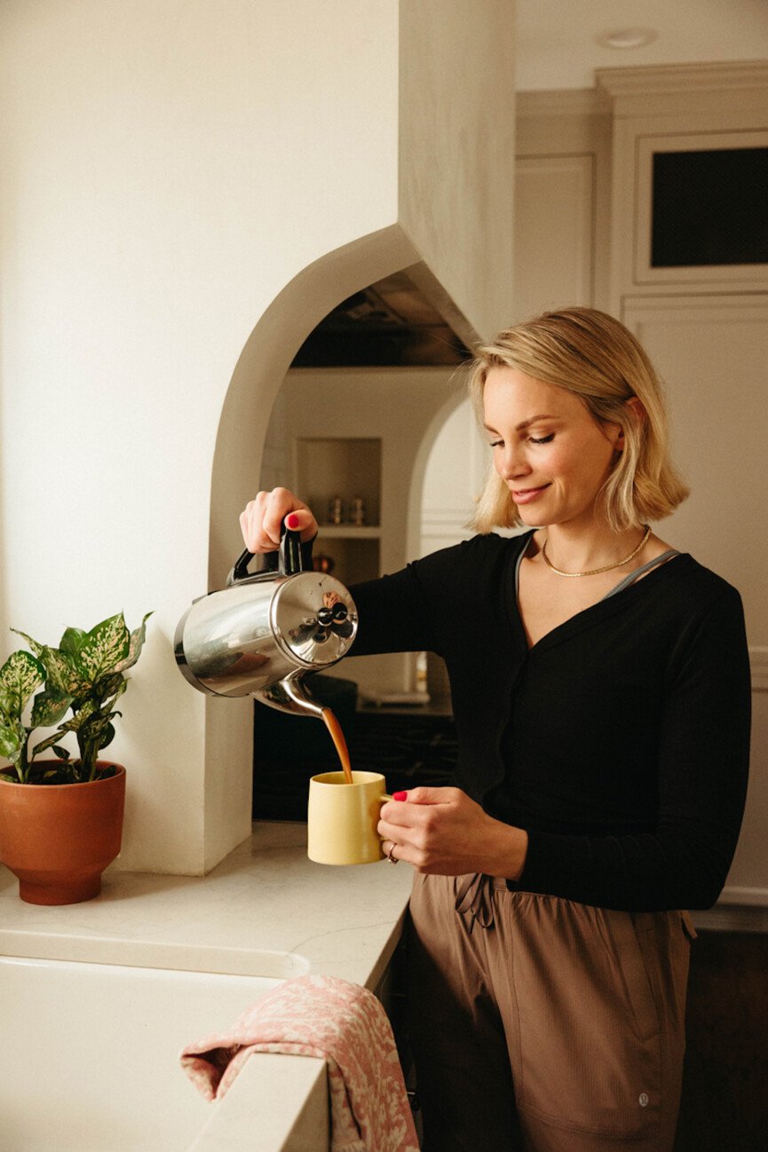 Woman pouring coffee into electric kettle.