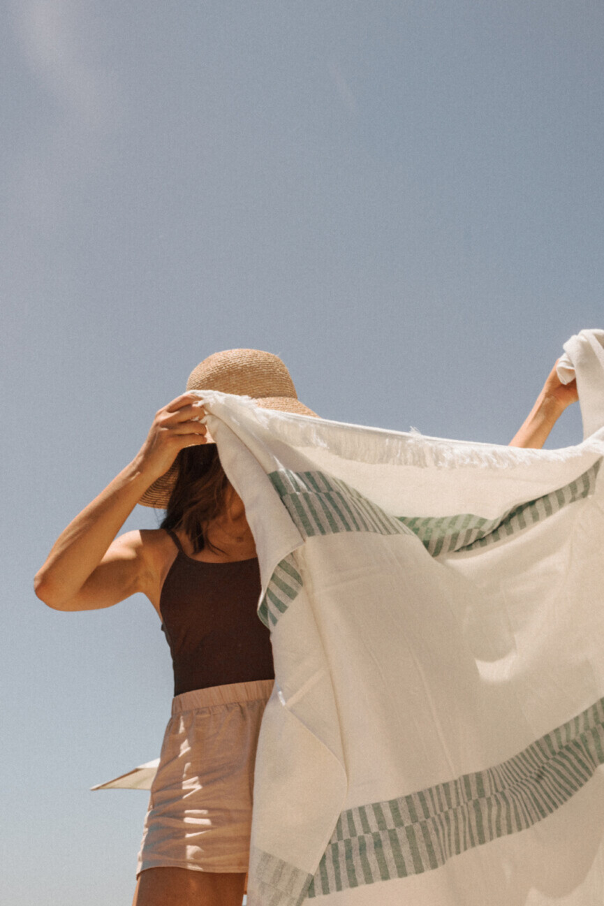 Mujer sacudiendo la toalla de playa.