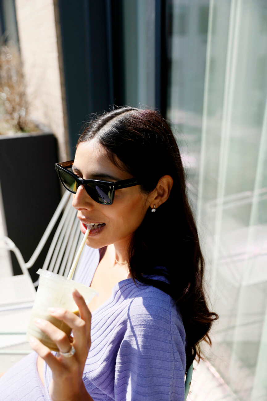 Woman wearing sunglasses drinking smoothie.