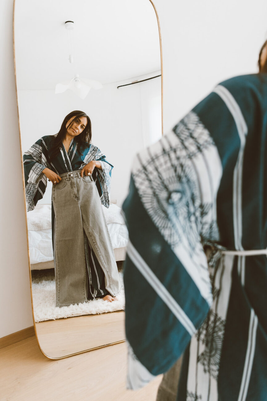 Woman trying on jeans in mirror.