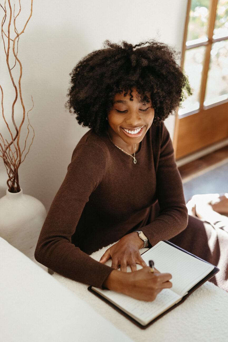 Woman journaling in notebook on computer.